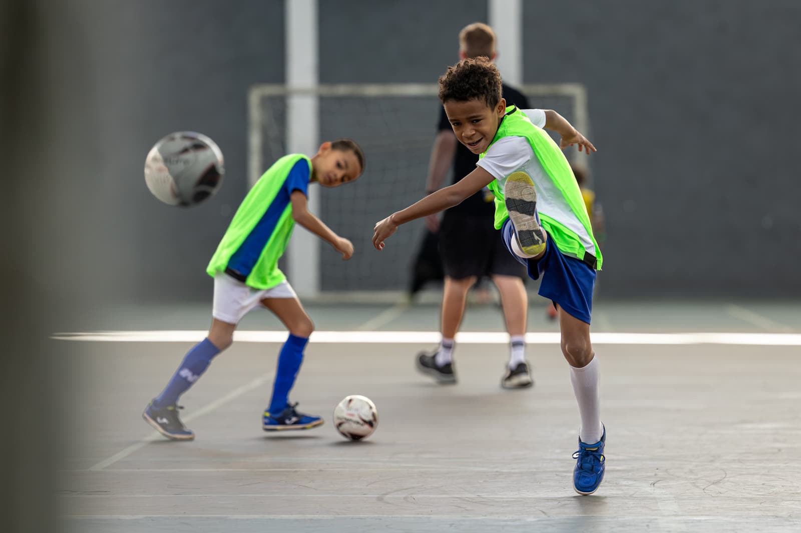 Disputa de bola em quadra coberta, banner H10 Futsal ao fundo