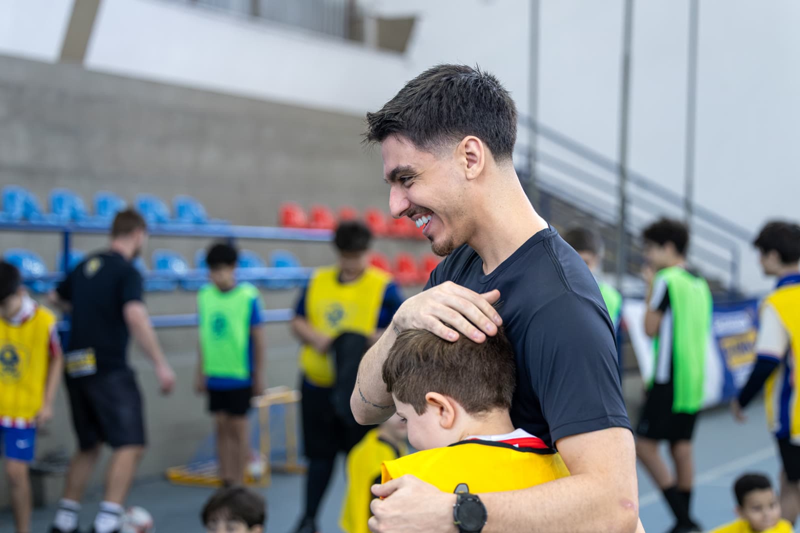 Treinador abraçando uma criança, os dois sorrindo